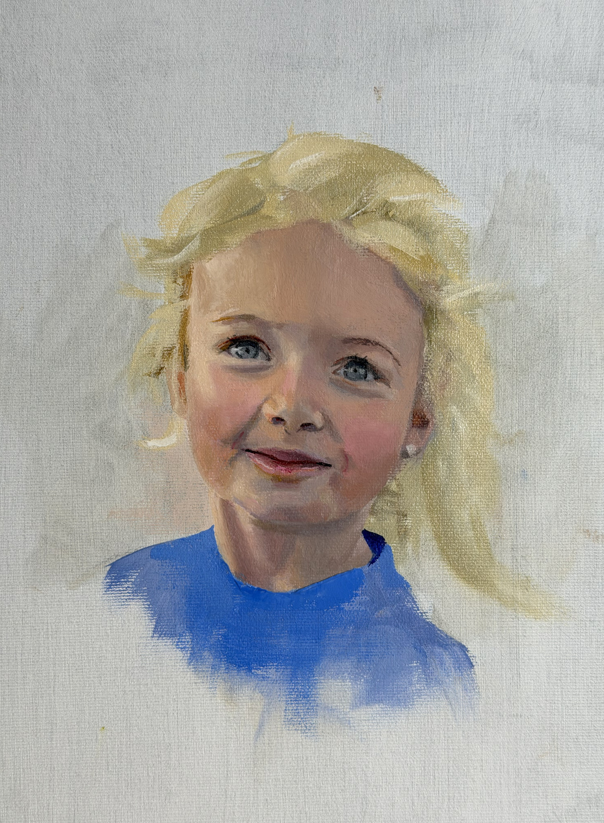 Portret van een blond meisje in een blauwe trui tegen een lichte achtergrond.